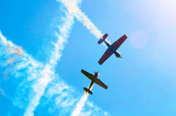 햇빛과 눈부심과 푸른 하늘에 그룹에 백색 연기의 흔적으로 가벼운 엔진 비행기. — 스톡 사진
