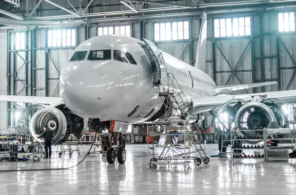 Пассажирские самолеты по техническому обслуживанию двигателя и ремонту фюзеляжа в ангаре аэропорта. — стоковое фото