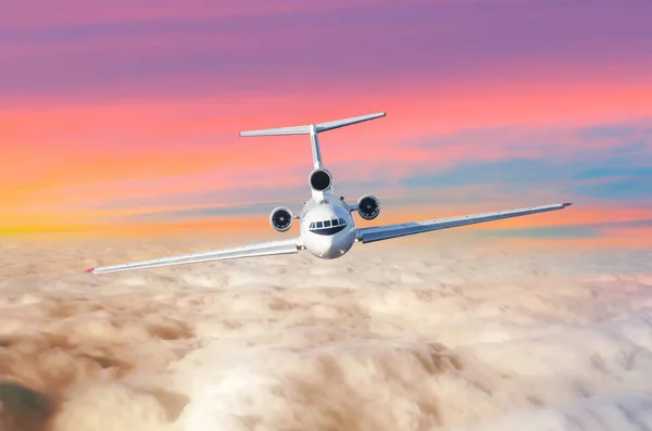 Passagerare flygplan med tre motorer på svansen flyga ovanför molnen Horisont himlen med ljusa sunset färger., utsikten är exakt på cockpiten på piloter. — Stockfoto