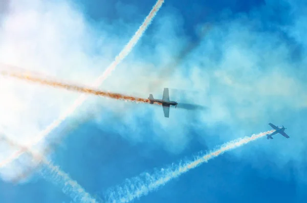 Avión de motor ligero con un rastro de humo blanco vuela en grupos en el cielo azul con luz solar y deslumbramiento . — Foto de Stock