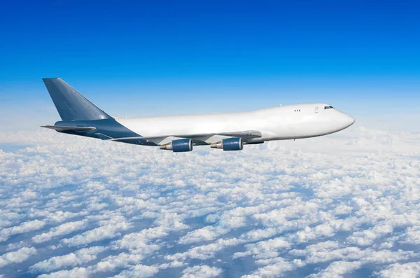Airplane with four engines, truck without portholes in the sky above the clouds flight journey sun height. — Stock Photo, Image