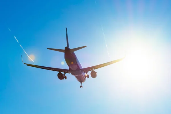 Aviones de pasajeros vuelan cerca del resplandor del sol en el aterrizaje, con las alas de un vórtice de vapor . — Foto de Stock
