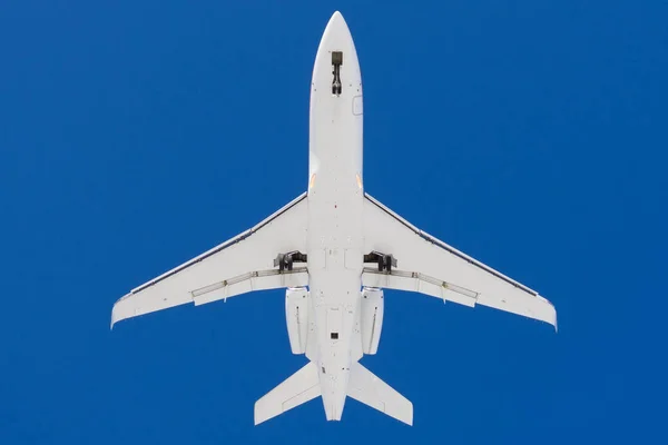 末尾にエンジンを搭載した小型旅客機。丁度下から眺め、青い空を背景にシルエット. — ストック写真