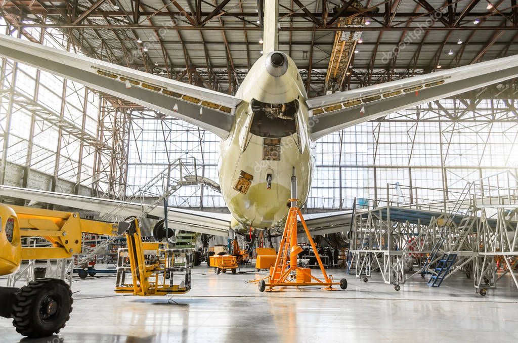 Passenger aircraft on service in an aviation hangar rear view of the tail, on the auxiliary power unit.