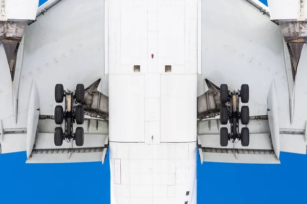 Вид снизу под летающим самолетом перед посадкой, в деталях шасси, крылья, закрылки, фюзеляж и двигатель. — стоковое фото