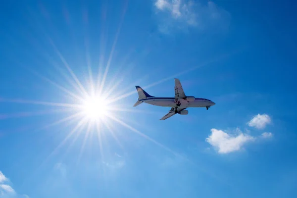 Avión de pasajeros vuela en un cielo azul con un sol brillante . — Foto de Stock