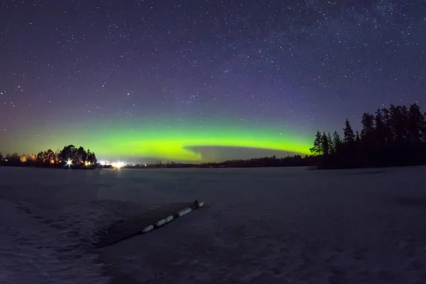 北极北极光在夜晚的星空下, 在湖上的繁星与岛屿和森林的剪影树木。地平线上闪耀的弧线. — 图库照片