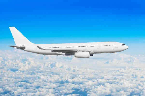 White passenger wide-body aircraft flies travel, trip at the flight level cumulus clouds, above against the blue sky. — Stock Photo, Image