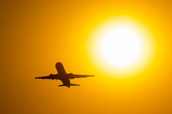 Silueta letadlo vzlétne při západu slunce, mouchy v blízkosti sluneční kotouč. — Stock fotografie
