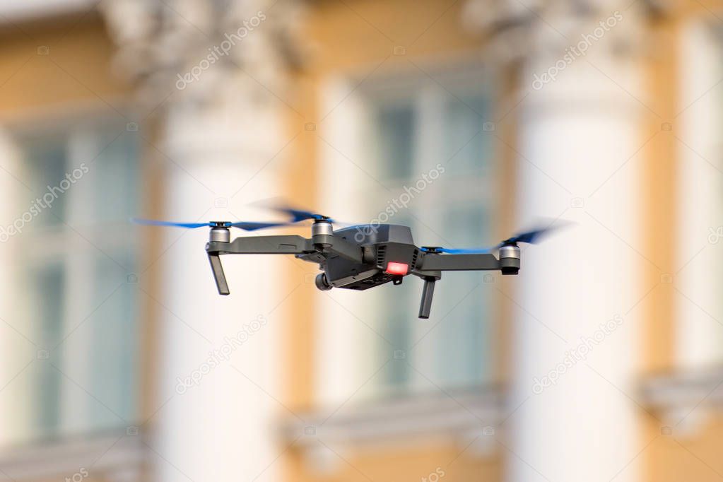 Drone quad copter is flying against the background of windows and columns of an ancient building.
