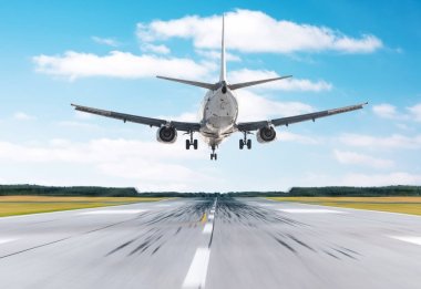 Yolcu uçağı, mavi gökyüzü bulutlu iyi açık havada bir piste iniş. Arkadan Görünüm.