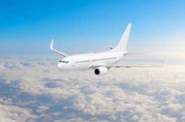 Yolcu uçak fly bir yüksekliği yukarıda mavi gökyüzü ve bulutlar üzerinde.