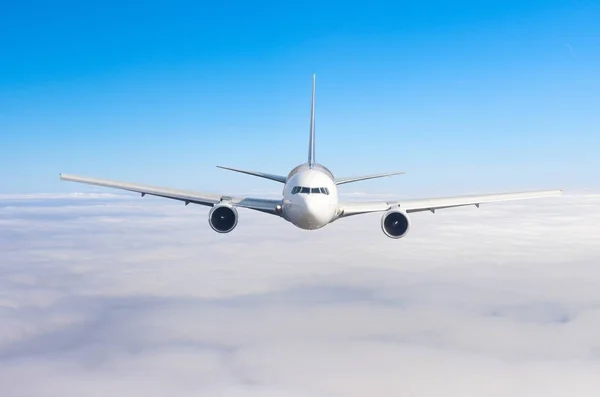 Passagier vliegtuig vliegen op vliegniveau hoog in de hemel boven bewolkte wolken en blauwe hemel. Kijk direct op de voorgrond, precies. — Stockfoto