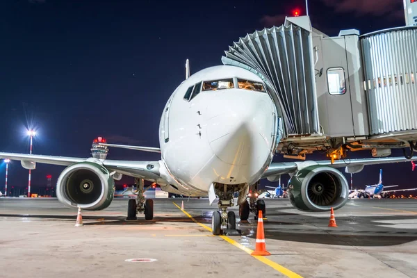 Avión de pasajeros en el aeropuente del telescopio en el servicio de vuelo nocturno del aeropuerto . — Foto de Stock