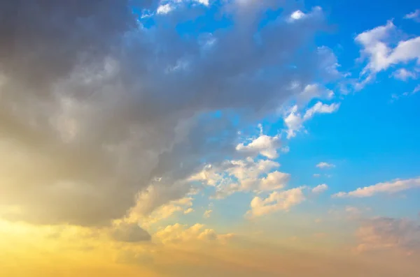 Flauschige Kumuluswolken vor Sonnenuntergang auf einem schönen Himmelsverlauf von blau nach orange. — Stockfoto