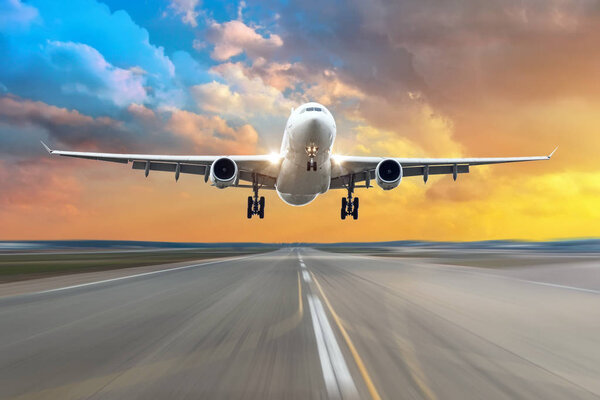 Прибытие самолета на взлетно-посадочную полосу вечером во время ярко-красного заката
.