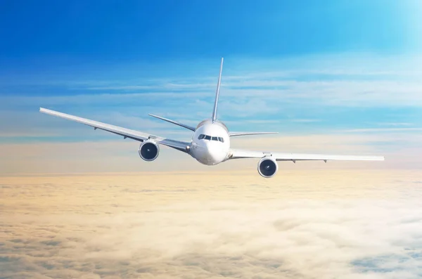 Passagier vliegtuig vliegen op vliegniveau hoog in de hemel boven bewolkte wolken en blauwe hemel. — Stockfoto