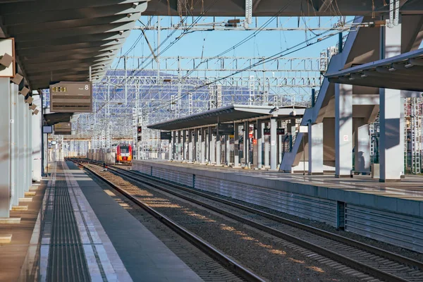 Personenbahnhof mit leerem Bahnsteig ohne Menschen, in der Ferne ist ein Zug zu sehen. — Stockfoto
