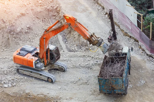 Carregando reforço de metal em um edifício destruído com uma escavadeira com um ímã . — Fotografia de Stock