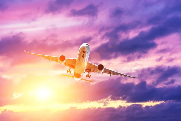 Vliegende passagiersvliegtuig tegen de achtergrond van 's avonds wolken verlicht door de zon. Het concept van toerisme, vakantie, reizen. — Stockfoto