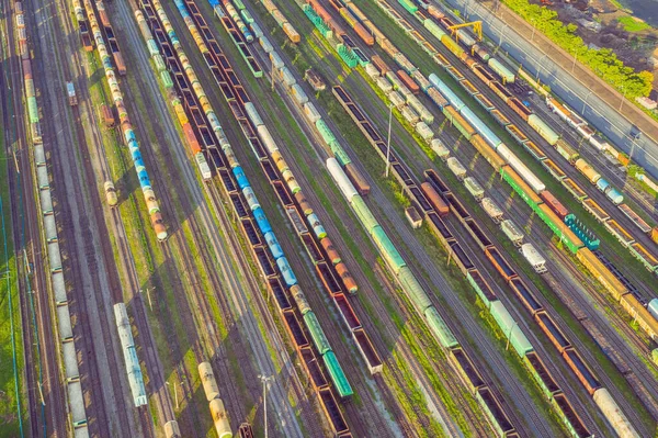 Vista aérea da estação ferroviária de triagem de carga com carros ferroviários, com muitos trilhos ferroviários ferrovia. Paisagem da indústria pesada na luz do pôr do sol à noite . — Fotografia de Stock