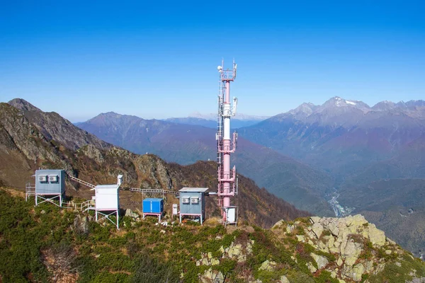 Komunikační věž s kabinami pro čerpací stanice a mobilní celu, na svazích hor. — Stock fotografie