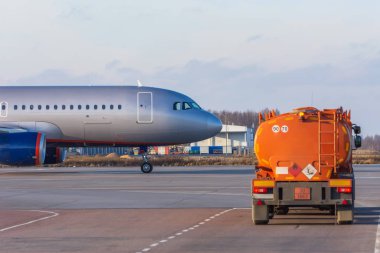 Havacılık yakıtı olan bir tanker, uçağa binmek üzere ayrılan bir taksici uçağı geçer..