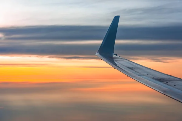 Wing of the plane lit by the sunrise on a background of sky. — Stock Photo, Image