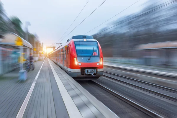 Vysokorychlostní červený vlak pro cestující s rozmazaným pohybem ve stanici. — Stock fotografie