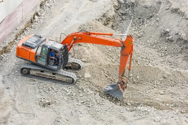 Червоний екскаватор викопує кам'янистий ґрунт, вид зверху . — стокове фото