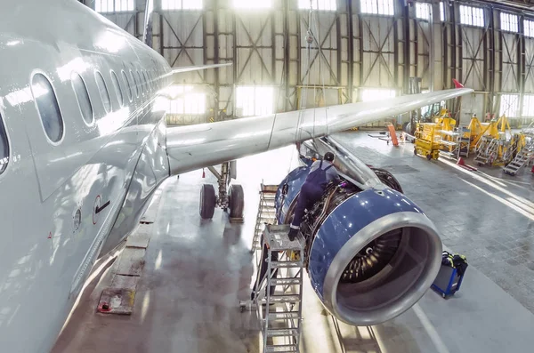 A working mechanic is repairing a passenger plane engine in a hangar. — 스톡 사진