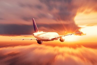 Akşam gökyüzü parlak bir günbatımı ve bir yolcu uçağı hareket hızıyla ufka doğru uçuyor.