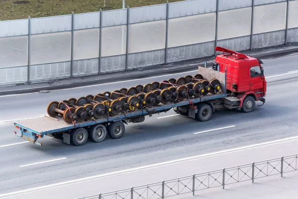 公路上开着敞篷拖车的商业运货卡车 车上装有火车上的轮 — 图库照片