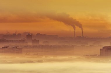 Caustik turuncu-sarı borular duman ve konut binaları. Kentsel manzara, bitki ve fabrikaların emisyonları yüzünden kirlenmiş atmosferi tütsüledi
