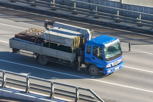 The small truck crane carries cargo on the highway