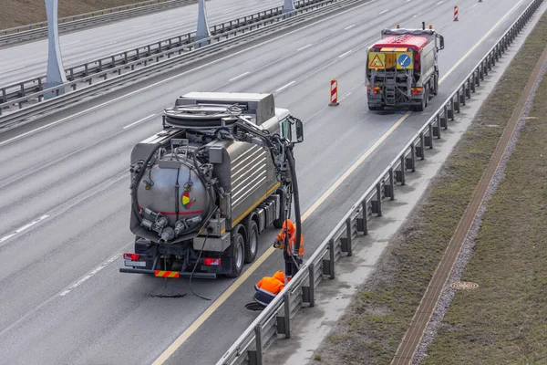 Sludge washer truck and workers specialists at work on the side of the highway to clean underground infrastructure, eliminate blockages in the sewer road sewage into the collector — Stock Image Sludge Washer Truck Workers Specialists Work Side Highway Clean Underground Stock Picture
