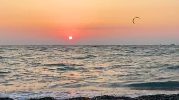 ビーチに波がある海の地平線の景色 遠くの人々は夏時間の日没時に夕方にカイトサーフィンに乗る — ストック動画
