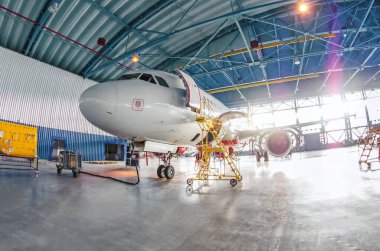 Geniş panoramik havacılık hangarları ve uçak bakımları, kapının dışında parlak ışıklar
