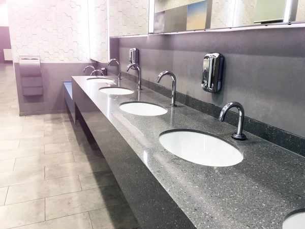 公衆トイレには水道水と石鹸のディスペンサーがあり 灰色のインテリアがあります — ストック写真