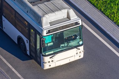 Yukarıdan beyaz bir yolcu otobüsü, bir kulübe ve otoyolda bir sürücü ön camı görünüyor.