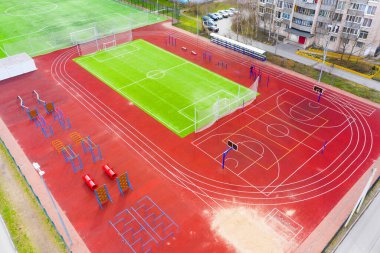 Futbol ve basketbol sahasında koşu bantları, yatay barlar ve spor sahasında diğer spor aletleri konut binalarının avlusunda.