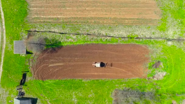 Tractor plows a small field in the village before planting vegetables spring. Aerial height view — Stock Footage Tractor Plows Small Field Village Planting Vegetables Spring Aerial Height Royalty Free Stock Footage