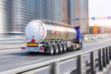 Krom metal bir sarnıçla dolu ağır bir kamyon cadde boyunca hızla ilerliyor.