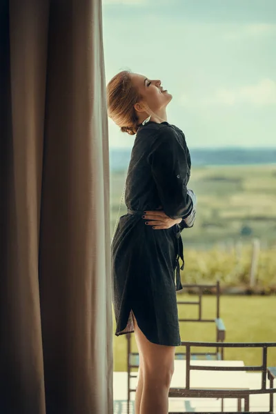 Woman wearing dress standing on balcony — Stock Photo, Image