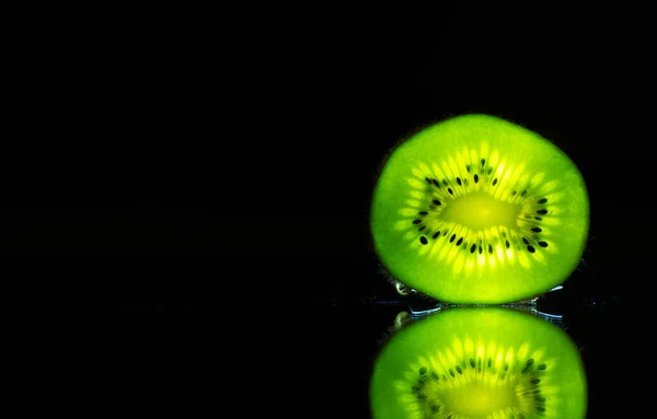 Kiwi illuminated by a flashlight on the mirror Photo taken at home, 4.04.2020, fruit, mirror, disk, water