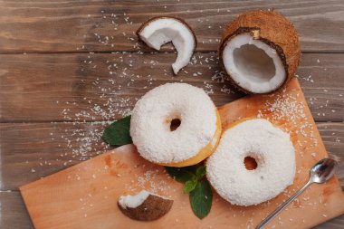 İki büyük hindistan cevizli çörek ve yanında da nane yaprağı ve hindistan cevizi parçaları var.