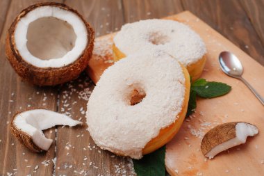İki büyük hindistan cevizli çörek ve yanında da nane yaprağı ve hindistan cevizi parçaları var.
