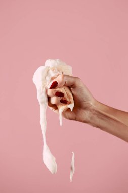 Dondurma elinde eriyor, pembe arka planda dondurma sıkıyor.