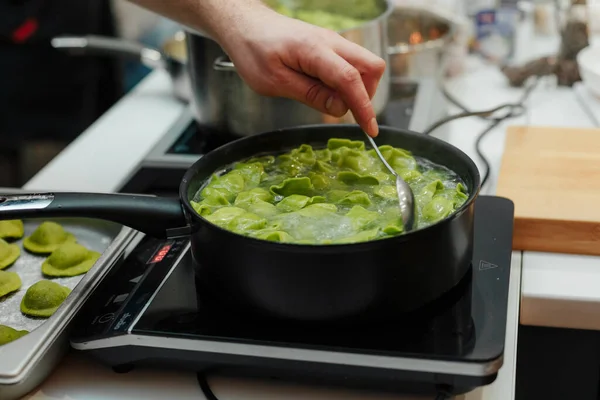 Cocinar ravioles frescos, de masa de espinacas en una sartén, pasta fresca italiana casera. Hervir en el agua hirviendo. Menú favorito familia . — Foto de Stock