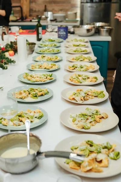 Muchas porciones de platos con ravioles en una mesa larga, comida amigable grande, cena familiar — Foto de Stock